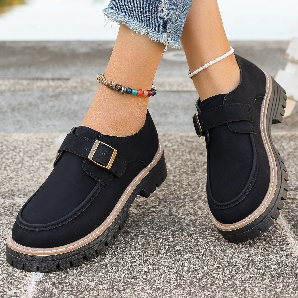 Schwarze Damen-Loafer mit Schnalle, dicker Sohle und Jeans. Modische Schuhe, ideal für Herbstmode. Bequeme, stilvolle Damen-Schuhe.
