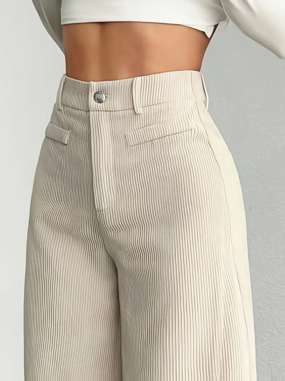 Beige, hoch taillierte, plissierte Hose aus Baumwolle, getragen von einer Person mit weißem Oberteil. Modetrend, Damenbekleidung, eleganter Stil.