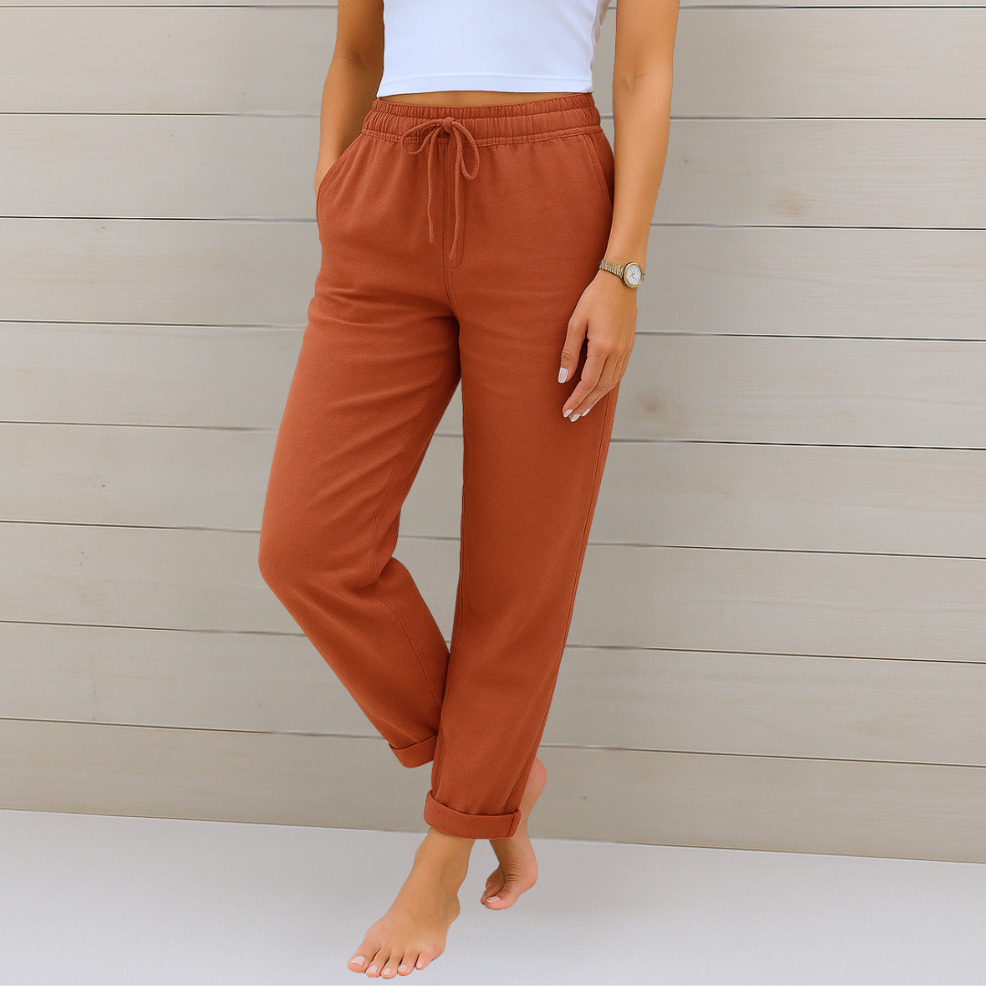 Frau in brauner Jogginghose und weißem Top vor Holzwand. Bequeme Damenmode, Freizeitlook, lässige Kleidung, moderne Jogginghose.