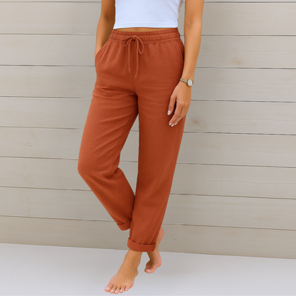 Frau in brauner Jogginghose und weißem Top vor Holzwand. Bequeme Damenmode, Freizeitlook, lässige Kleidung, moderne Jogginghose.