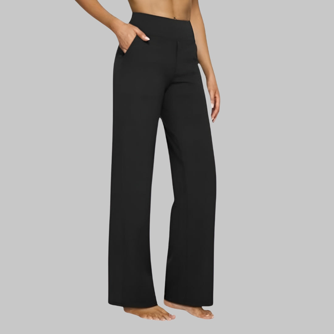 Frau trägt schwarze, weite Hose mit Taschen, stehend vor grauem Hintergrund. Modische Damenbekleidung, bequem und elegant.