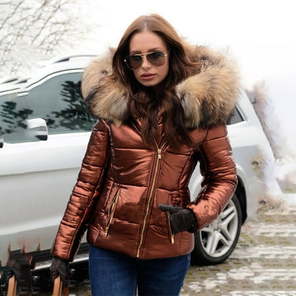 Frau in glänzender, kupferfarbener Daunenjacke mit Fellkapuze, Sonnenbrille, vor schneebedecktem Auto. Wintermode, stilvolle Damenbekleidung.