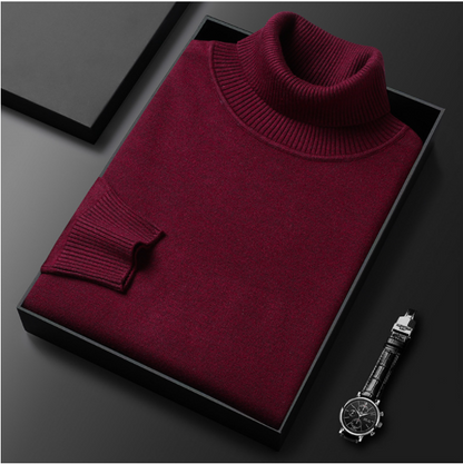 Bordeauxroter Rollkragenpullover in Geschenkbox, elegantes Design, hochwertige Strickmode, neben schwarzer Armbanduhr auf grauem Hintergrund.