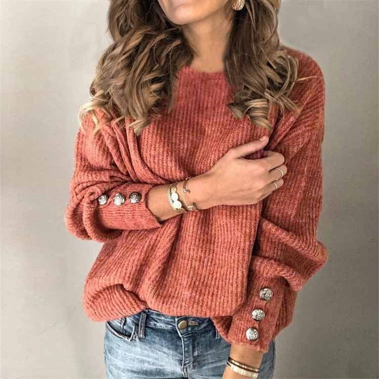 Frau in rotem Strickpullover mit Knöpfen an den Ärmeln, trägt Jeans und Schmuck. Modetrend, Herbstmode, Damenbekleidung, lässiger Stil.