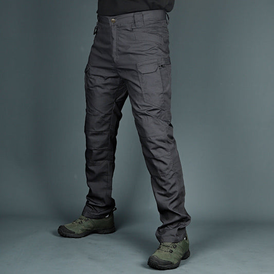 Graue taktische Hose mit mehreren Taschen, getragen von einer Person, kombiniert mit olivgrünen Wanderschuhen. Ideal für Outdoor-Aktivitäten.