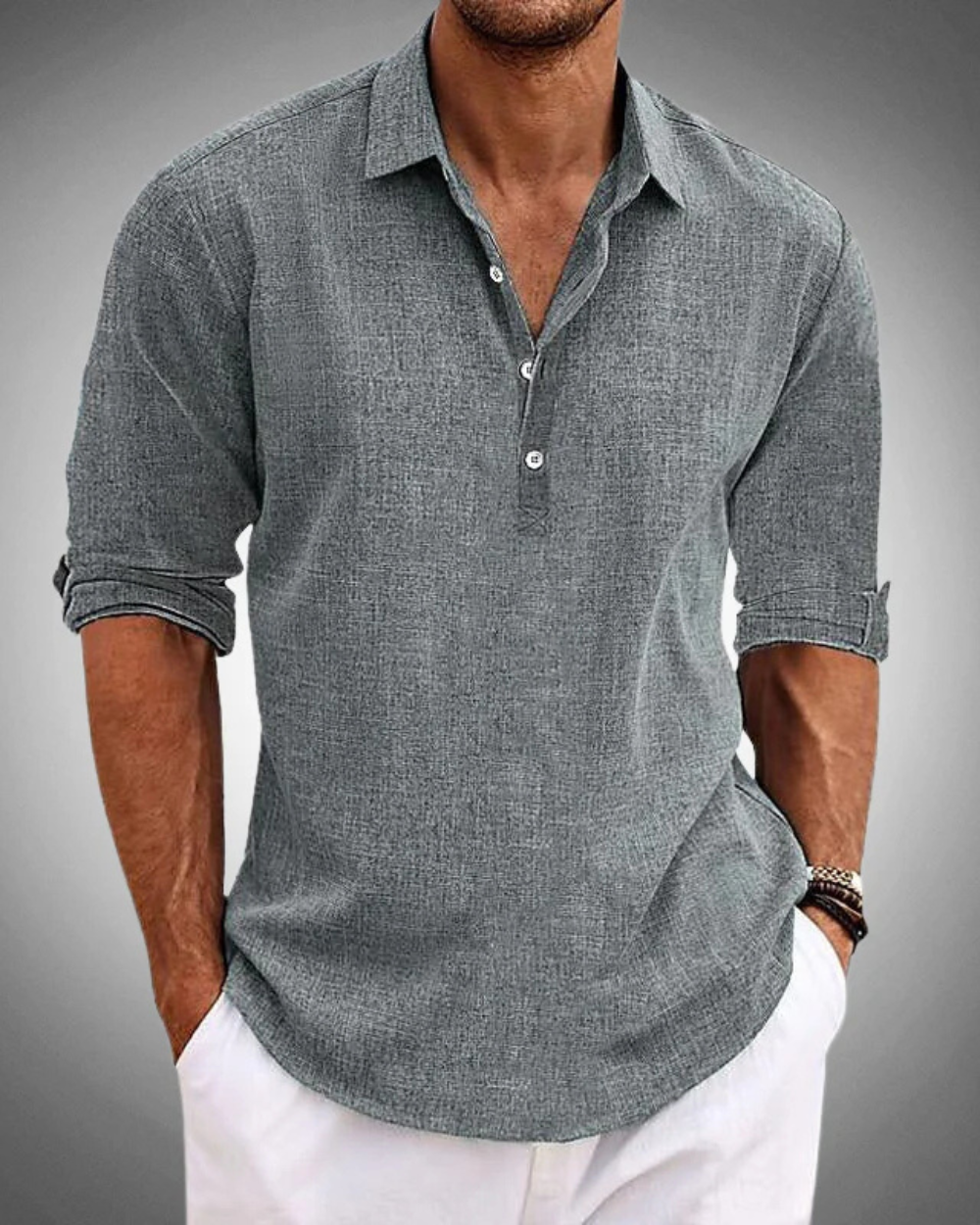 Graues Leinenhemd für Herren, langärmlig, lässig, mit Knopfleiste, kombiniert mit weißen Hosen. Ideal für Sommermode und Freizeitkleidung.