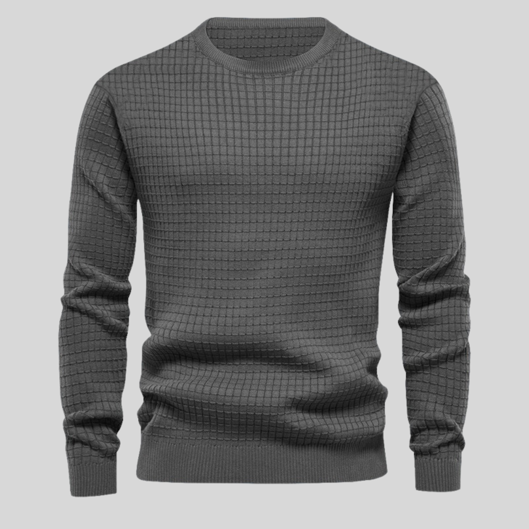 Grauer Strickpullover mit Karomuster, Rundhalsausschnitt und langen Ärmeln auf grauem Hintergrund. Modischer Herrenpullover, warm und stilvoll.