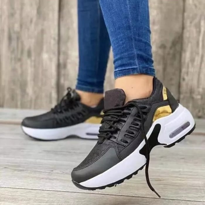 Damen Sneaker in Schwarz mit goldenen Akzenten, weiße Sohle, getragen mit blauen Jeans. Modische Sportschuhe, ideal für Freizeit und Sport.