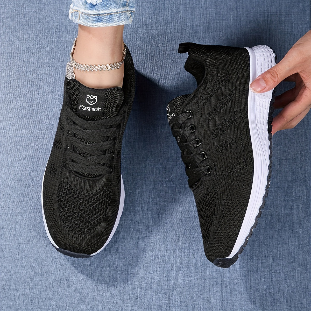 Schwarze Damen-Sneaker mit weißer Sohle, modisches Design, auf blauem Hintergrund. Bequeme Sportschuhe, ideal für Freizeit und Sport.