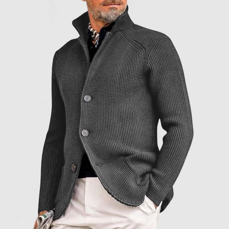 Eleganter Mann in grauem Strickblazer, kombiniert mit schwarzem Hemd und beiger Hose. Stilvolle Herrenmode, modern und zeitlos.