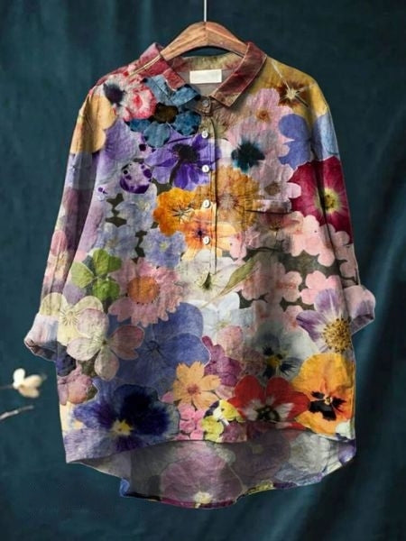 Bunte Damenbluse mit Blumenmuster auf Kleiderbügel vor dunkelblauem Hintergrund. Modische, florale Oberbekleidung, ideal für Frühling und Sommer.