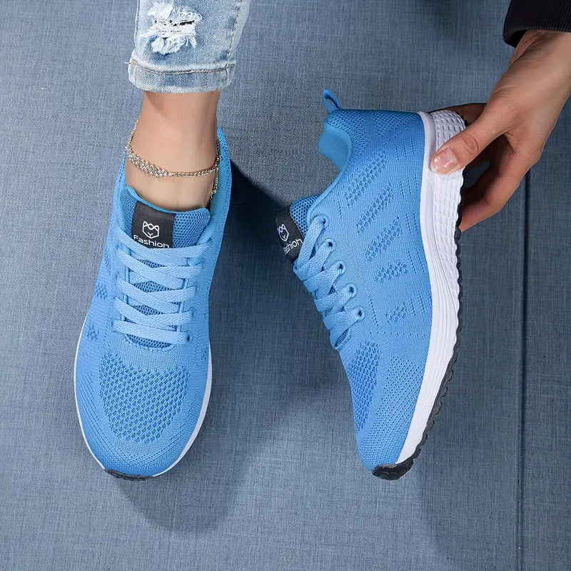 Blaue Sportschuhe mit weißer Sohle auf Jeansstoff, getragen von Person mit Jeans. Moderne, atmungsaktive Sneaker für Damen.