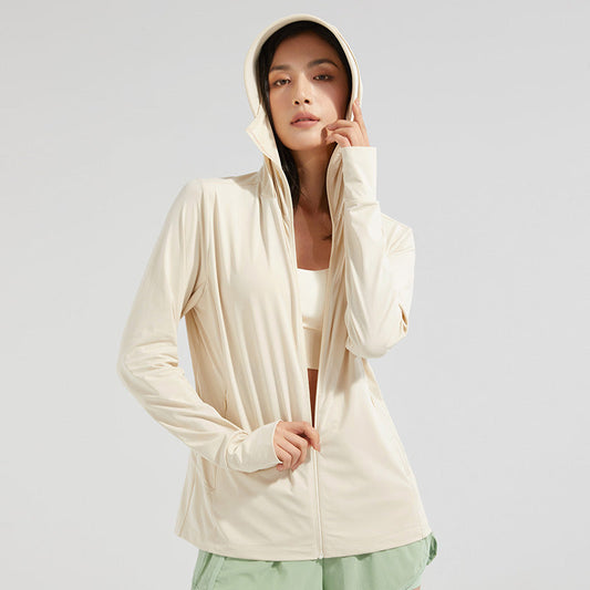 Frau in beiger Sportjacke mit Kapuze, trägt grünen Rock. Modische Sportbekleidung, ideal für Fitness und Freizeit. Minimalistischer Stil.