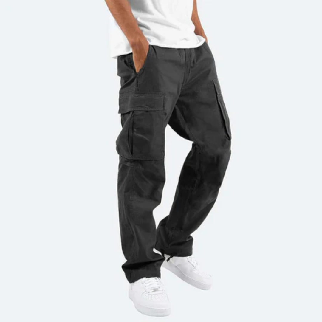 Mann trägt schwarze Cargohose und weiße Sneaker, lässiger Stil, Hände in den Taschen, modische Herrenbekleidung, urbaner Look.
