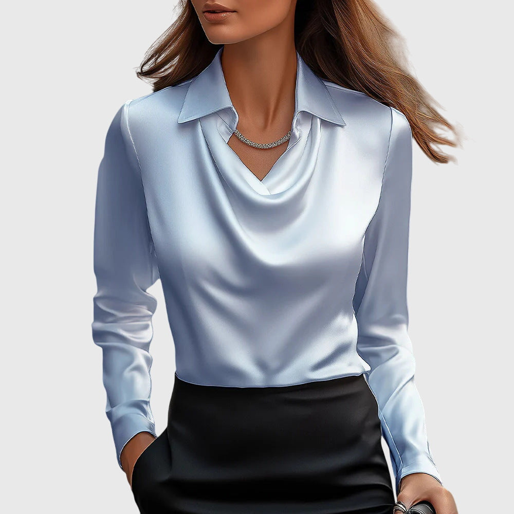 Frau in eleganter, hellblauer Seidenbluse mit Wasserfallausschnitt und schwarzem Rock, trägt eine dezente Halskette. Mode, Damenbekleidung, Stil.
