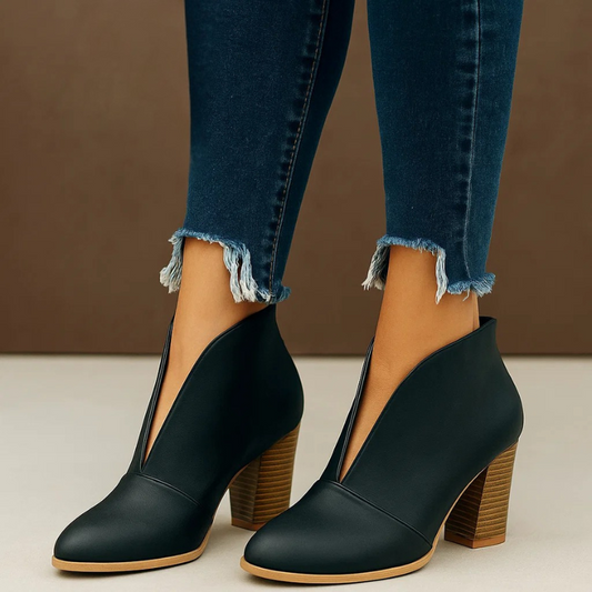 Damenstiefeletten mit Blockabsatz, schwarzes Leder, V-Ausschnitt, kombiniert mit dunkelblauen, ausgefransten Jeans. Modische Herbstschuhe.