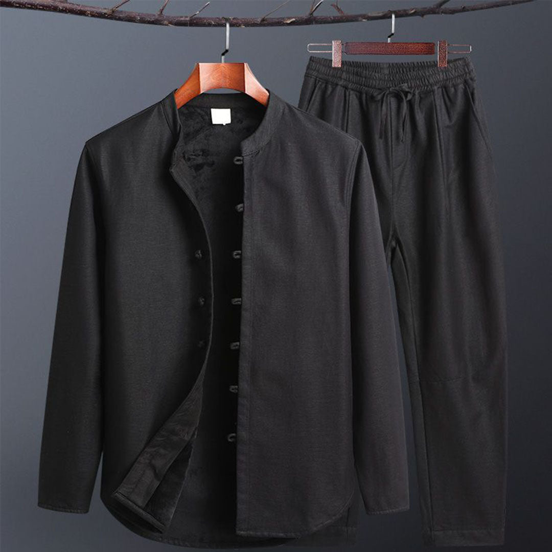 Schwarzer Herrenanzug aus Baumwolle, bestehend aus langärmligem Hemd mit Stehkragen und passender Hose. Elegante, minimalistische Herrenmode.