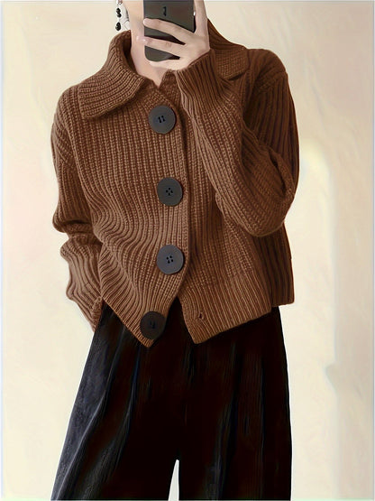 Braune Strickjacke mit großen Knöpfen, getragen von Person, die ein Smartphone hält. Modetrend, Herbstmode, Damenbekleidung, stilvoller Look.