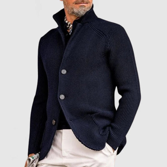 Dunkelblauer Strickblazer für Herren, elegant und modern, mit Knopfleiste, kombiniert mit weißer Hose. Perfekt für stilvolle Herbstmode.