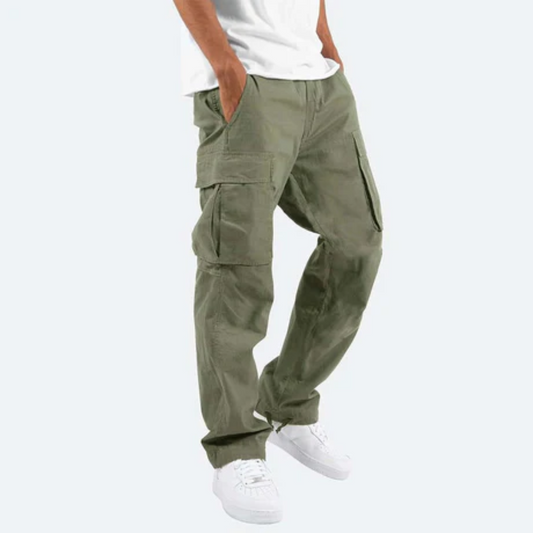 Mann trägt olivgrüne Cargo-Hose mit Seitentaschen, kombiniert mit weißen Sneakers und weißem T-Shirt. Modetrend, lässiger Stil, Herrenbekleidung.