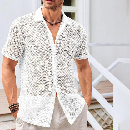 Mann in weißem, durchsichtigen Häkelhemd, lässig und stilvoll, steht vor einem modernen Gebäude. Sommermode, Herrenbekleidung, Freizeitlook.