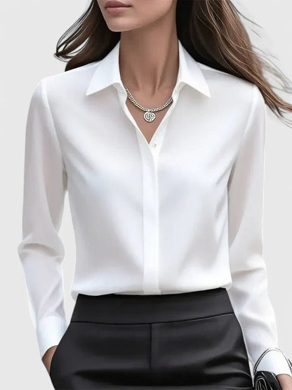 Frau in eleganter weißer Bluse mit Kragen und Kette, kombiniert mit schwarzer Hose. Businessmode, Damenbekleidung, stilvoller Büro-Look.