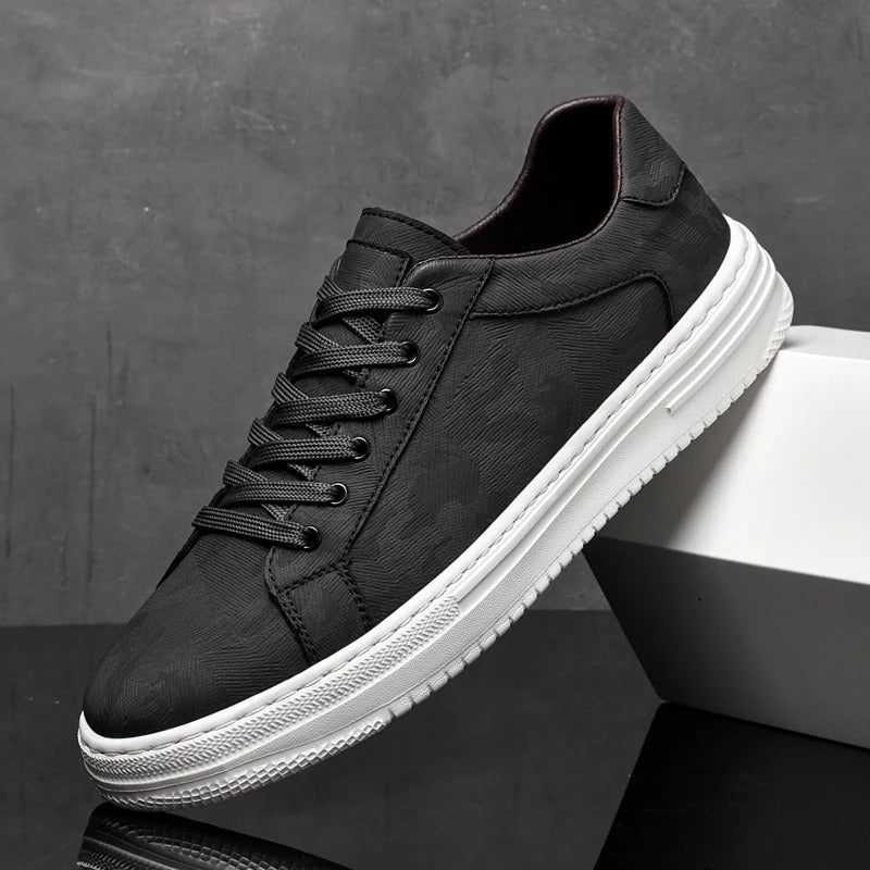 Schwarzer Sneaker mit weißer Sohle, seitlich aufgestellt vor grauem Hintergrund. Moderner Herrenschuh, ideal für Freizeit und Alltag.
