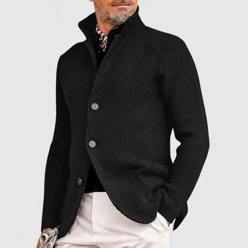 Schwarzer Herrenstrickjacke mit Knöpfen, eleganter Look, kombiniert mit weißer Hose und gemustertem Schal, ideal für stilvolle Herbstmode.