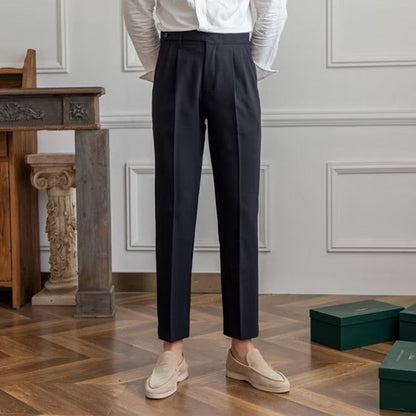 Elegante Herrenanzughose in Dunkelblau, kombiniert mit beigen Loafers. Perfekt für formelle Anlässe. Moderner, stilvoller Look auf Holzboden.