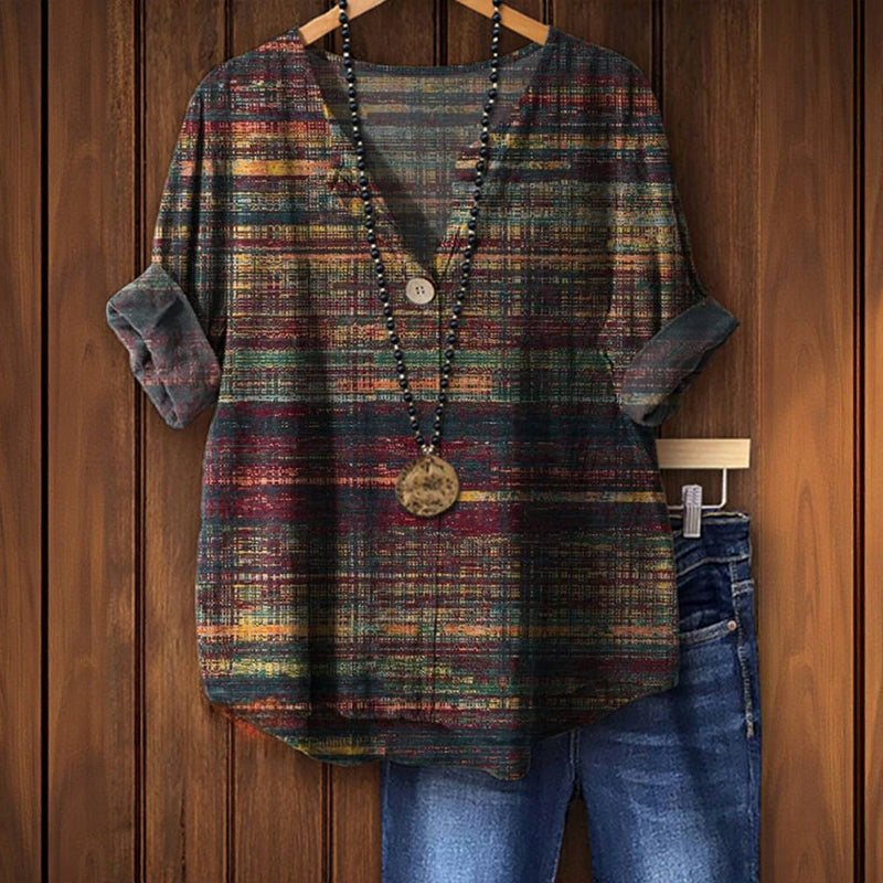 Bunte karierte Bluse mit V-Ausschnitt und Holzknopf, kombiniert mit blauer Jeans, hängend vor Holzwand. Modetrend, Damenbekleidung, Freizeitlook.