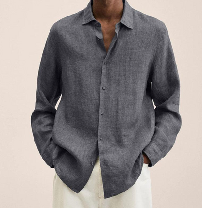 Graues Leinenhemd für Herren, lässig offen getragen, kombiniert mit weißen Hosen. Stilvolle Herrenmode, ideal für Sommer und Freizeit.
