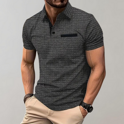 Mann in grauem Polohemd mit kurzen Ärmeln, muskulös, trägt beige Hose und Armbanduhr. Mode, Herrenbekleidung, Freizeitlook.