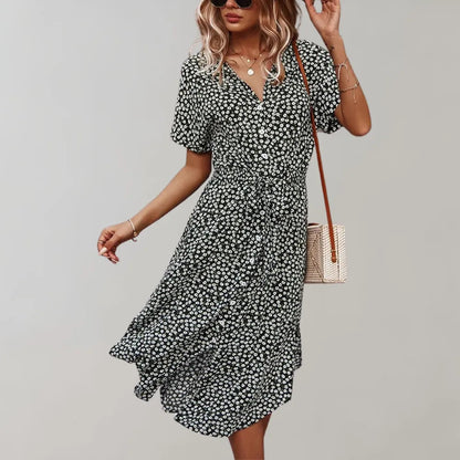 Frau in geblümtem Sommerkleid, schwarz-weiß, mit V-Ausschnitt und kurzen Ärmeln, trägt Umhängetasche. Modetrend, Damenmode, Freizeitkleidung.