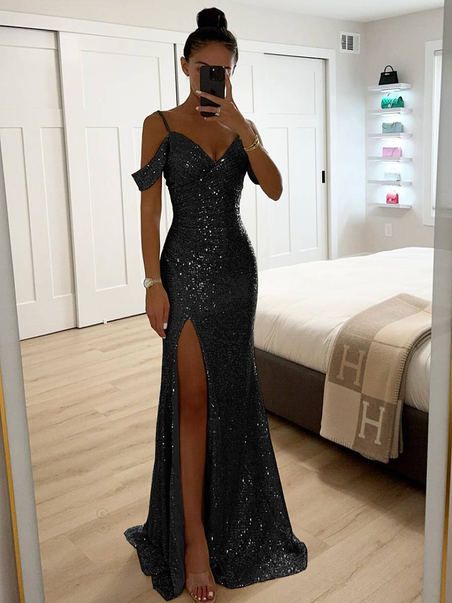 Frau in elegantem, schwarzem Paillettenkleid mit hohem Beinschlitz, steht in modernem Schlafzimmer, macht Selfie vor Spiegel.