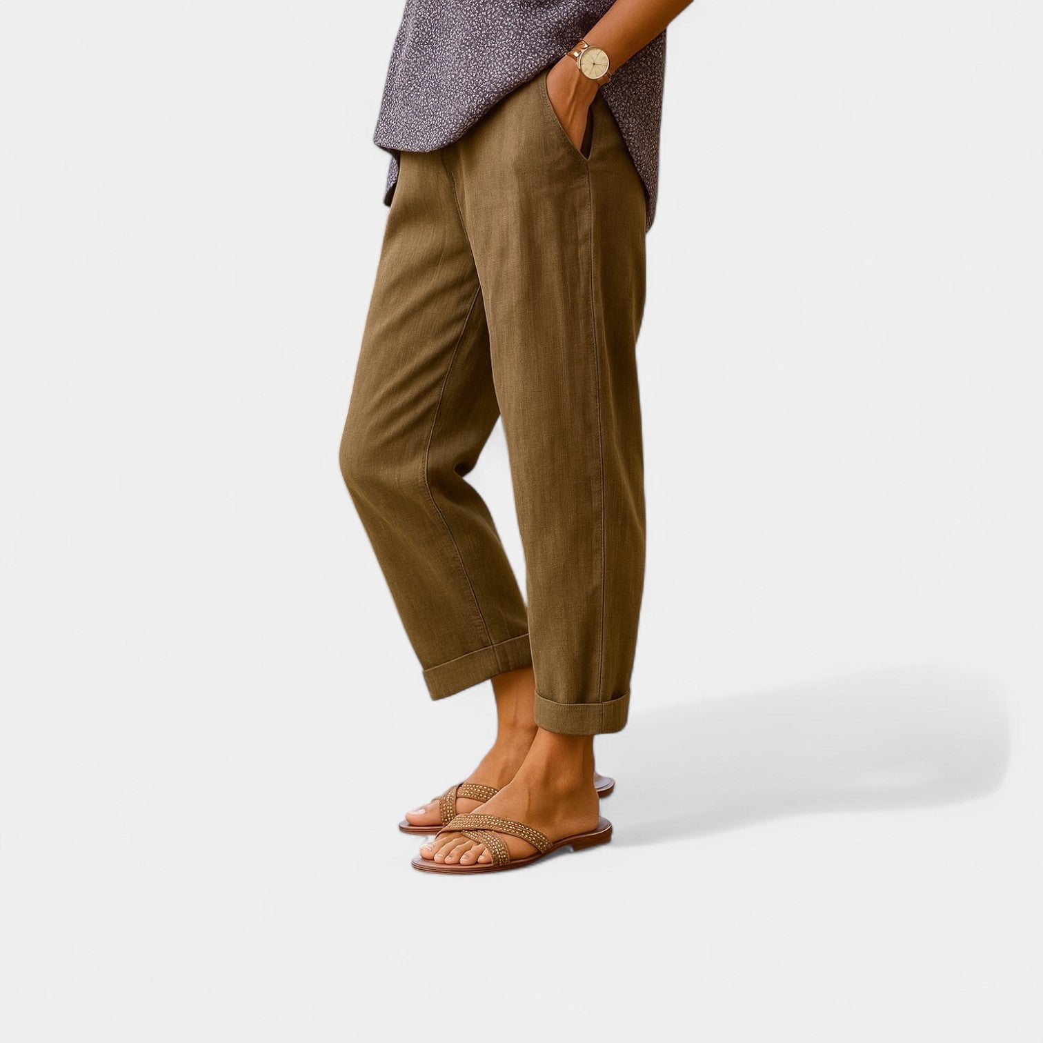 Frau in brauner Leinenhose und Sandalen, lässiger Look, Sommermode, seitliche Ansicht, Hände in Taschen, minimalistischer Stil.