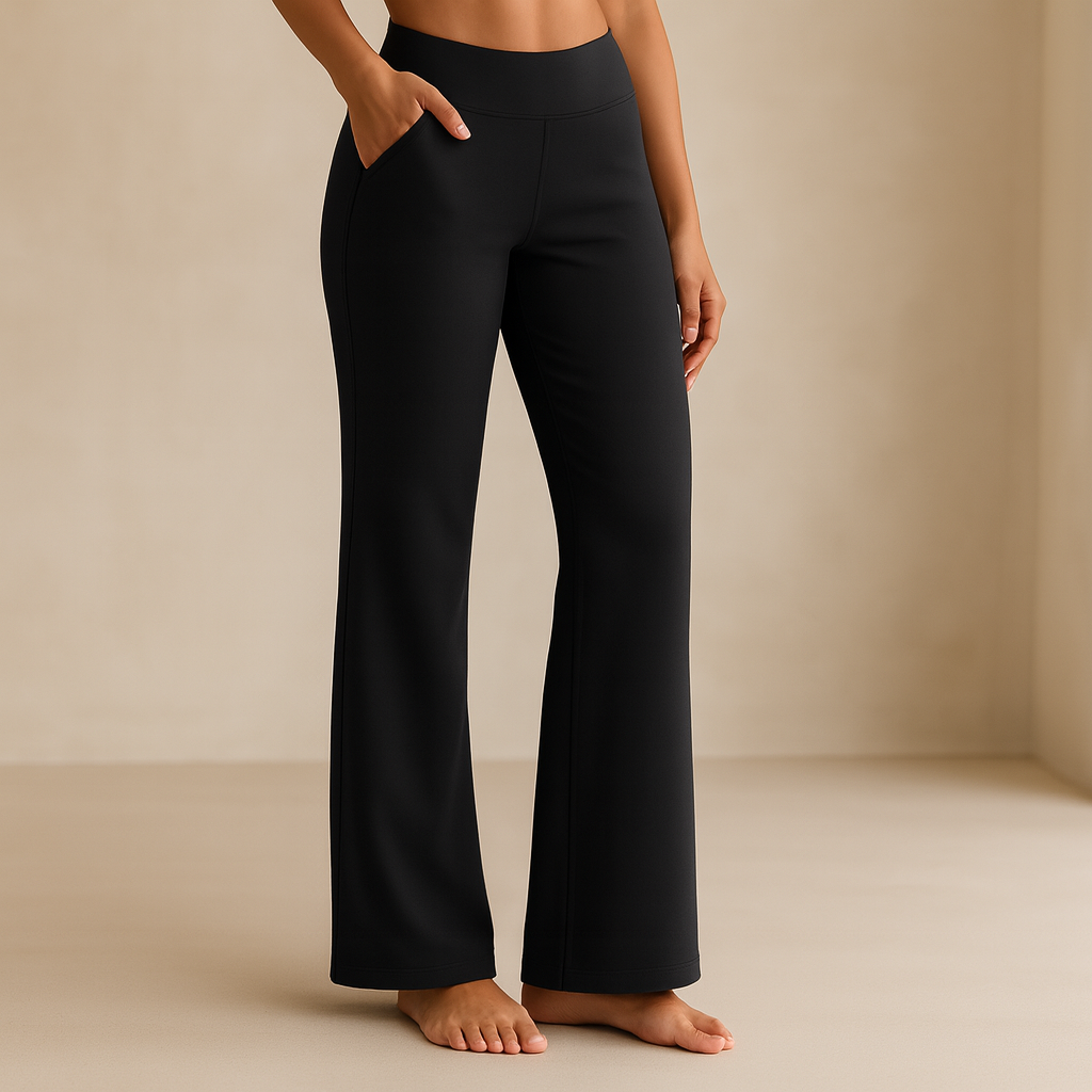 Frau in schwarzen Yoga-Hosen, Bootcut-Stil, barfuß auf beigem Hintergrund. Bequeme Sportbekleidung, ideal für Fitness und Freizeit.