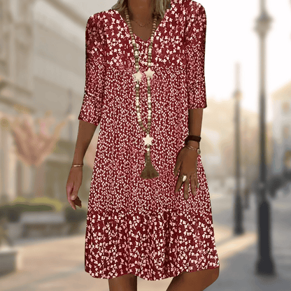 Rotes geblümtes Sommerkleid mit Dreiviertelärmeln, getragen von einer Frau auf einer städtischen Straße. Perfekt für lässige Mode und Sommeroutfits.