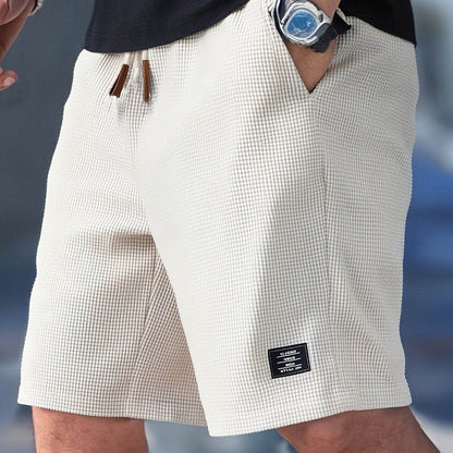 White shorts worn by a person with a watch on a blue background
