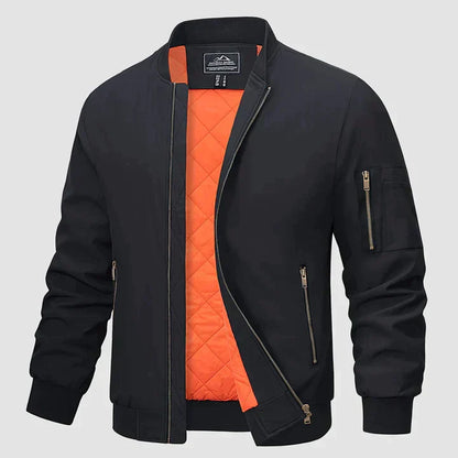 Schwarze Bomberjacke mit orangefarbenem Innenfutter, Reißverschlusstaschen und geripptem Kragen. Modische Herrenjacke für Herbst und Winter.