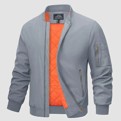 Graue Bomberjacke mit orangefarbenem Innenfutter, Reißverschlusstaschen und gerippten Bündchen. Modische Herrenjacke, ideal für Herbst und Frühling.