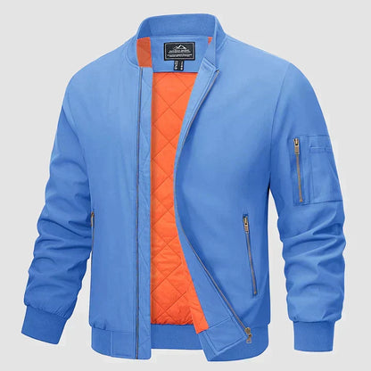 Blaue Bomberjacke mit orangefarbenem Innenfutter, Reißverschlusstaschen und gerippten Bündchen. Modische Herrenjacke, ideal für Herbst und Frühling.