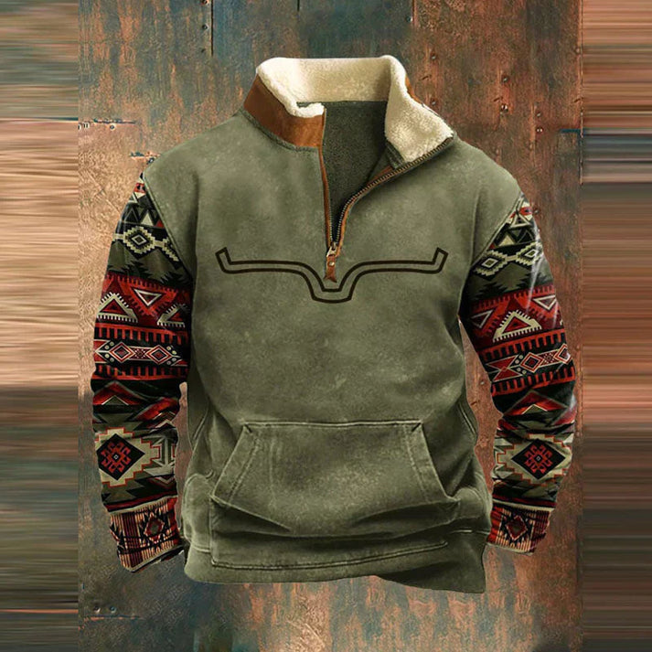 Grüner Herrenpullover mit Aztekenmuster-Ärmeln, Reißverschluss und Kängurutasche vor rustikalem Hintergrund. Modischer Winterpullover.