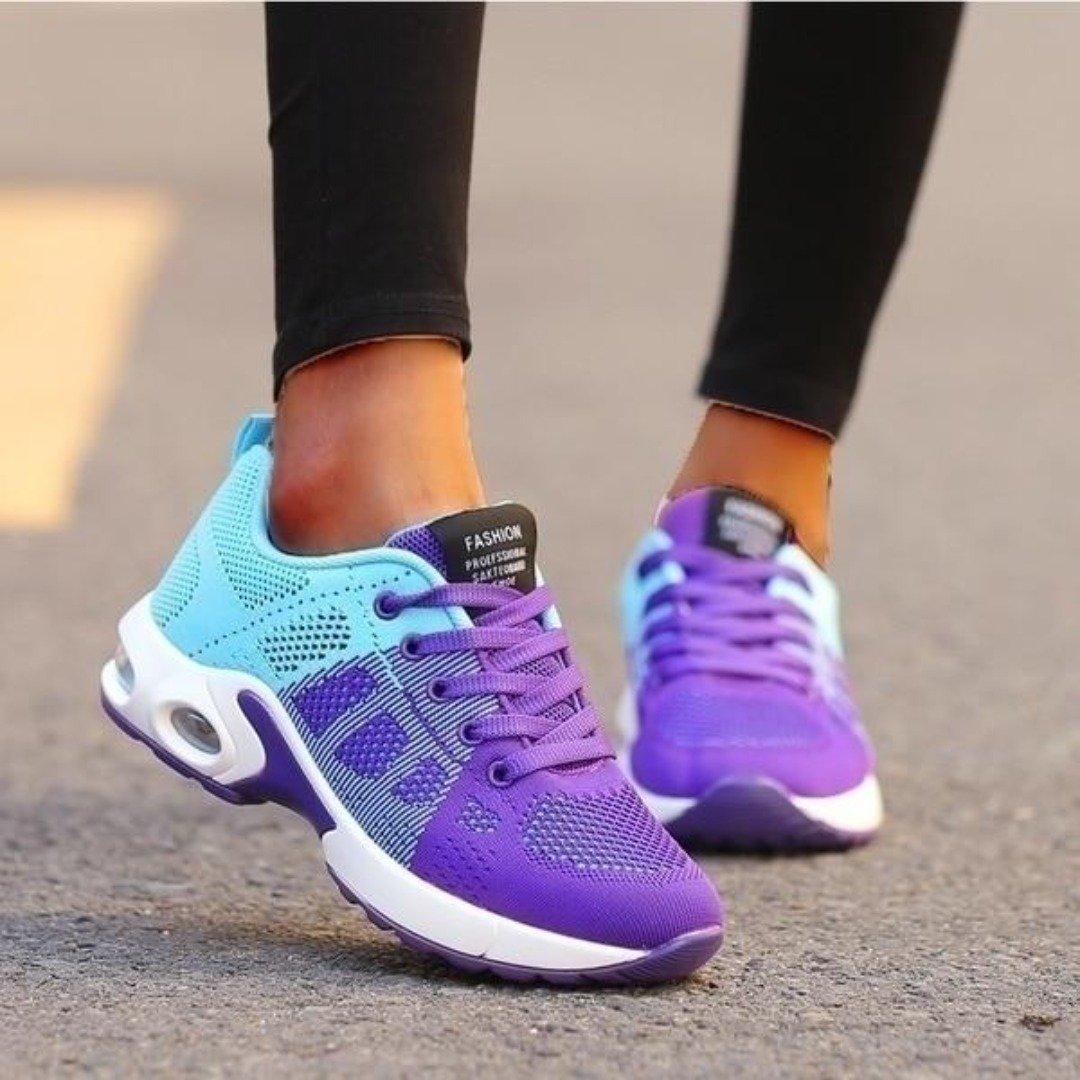 Frau trägt lila-blau Sportschuhe auf Asphalt. Modische Damen Sneaker, atmungsaktiv, ideal für Laufen und Fitness. Trendige Sportmode.