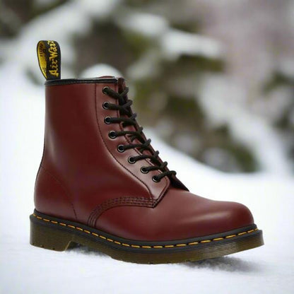 Klassischer brauner Lederstiefel im Schnee, robustes Design, gelbe Naht, ideal für Wintermode und Outdoor-Aktivitäten.