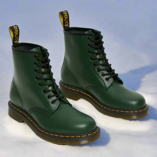 Grüne Lederstiefel auf Schnee, klassische Schnürstiefel mit gelber Naht, robustes Design, ideal für Wintermode und Outdoor-Aktivitäten.