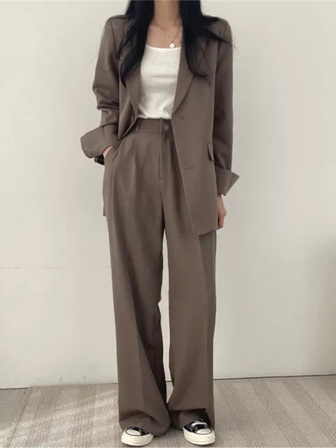 Frau in braunem Anzug mit weißem T-Shirt und Sneakers, lässiger Business-Look, Mode für Damen, eleganter Hosenanzug, moderne Büro-Outfits.