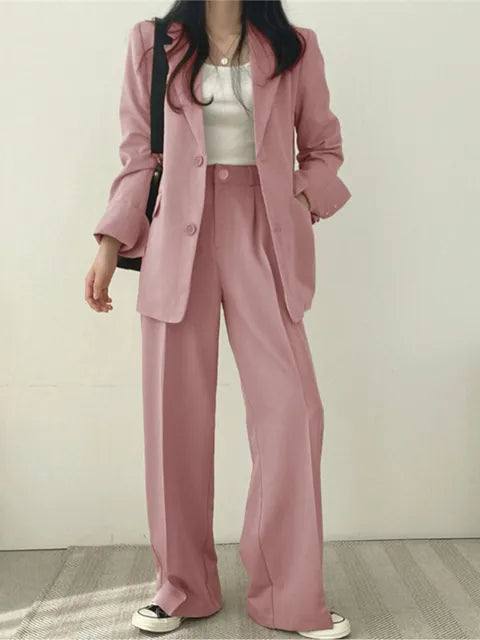 Frau in rosa Anzug mit weißem Top und Sneakers, modisches Business-Outfit, lässiger Stil, moderne Damenmode, eleganter Look.