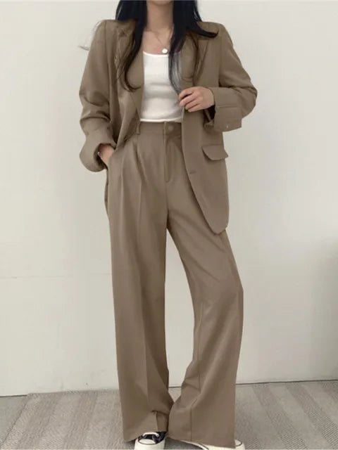 Frau in beigem Anzug mit weißem Top und Sneakers, modischer Business-Look, lässiger Stil, elegante Damenbekleidung, zeitgemäße Mode.