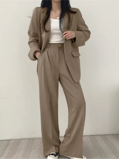 Frau in beigem Anzug mit weißem Top und Sneakers, modischer Business-Look, lässiger Stil, elegante Damenbekleidung, zeitgemäße Mode.