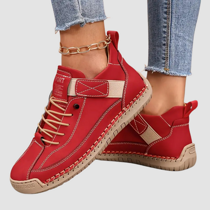 Rote Damen-Sneaker mit beigem Akzent, getragen mit blauen Jeans und goldener Knöchelkette. Modische Freizeitschuhe für Damen.